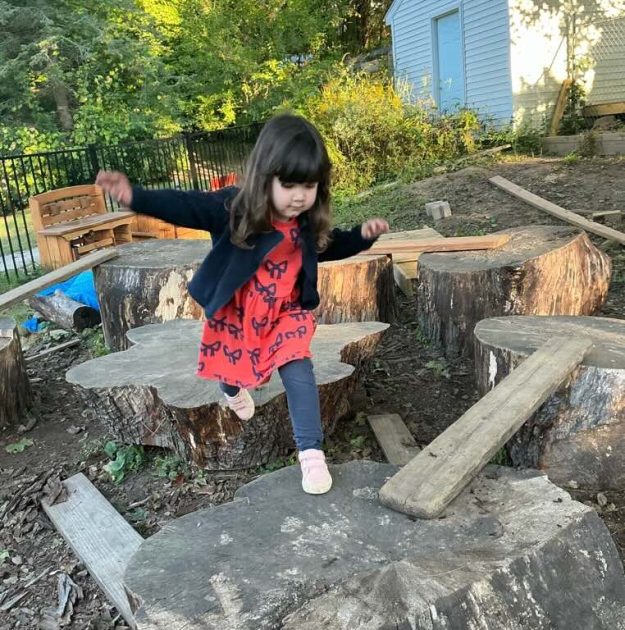 A preschooler hops between large rocks