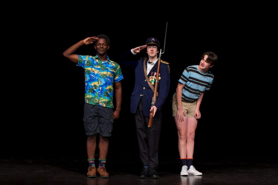 Skyline's Leaving Iowa - actors on stage one in Hawaiian shirt salutes, one in uniform salutes, thrid leans away