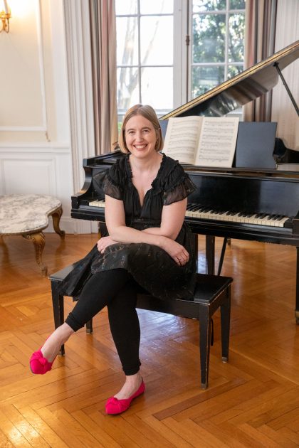 Pianist Anne Lovering Rounds sits at a bench in front of a grand piano