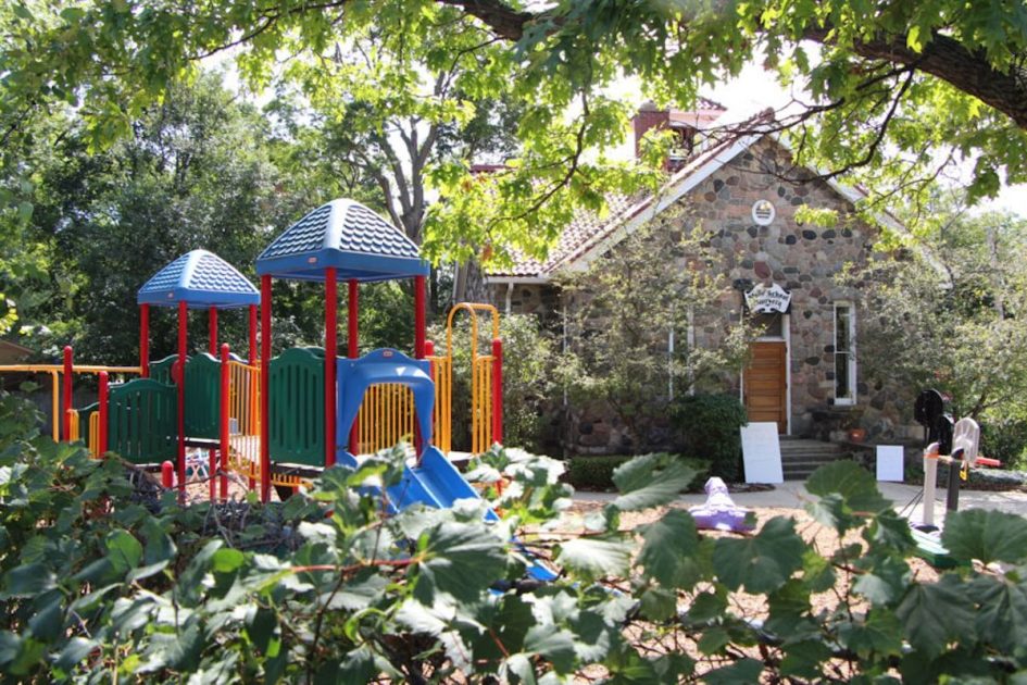 Stone School Cooperative Preschool - the historic Stone School building with playground and trees in full bloom.