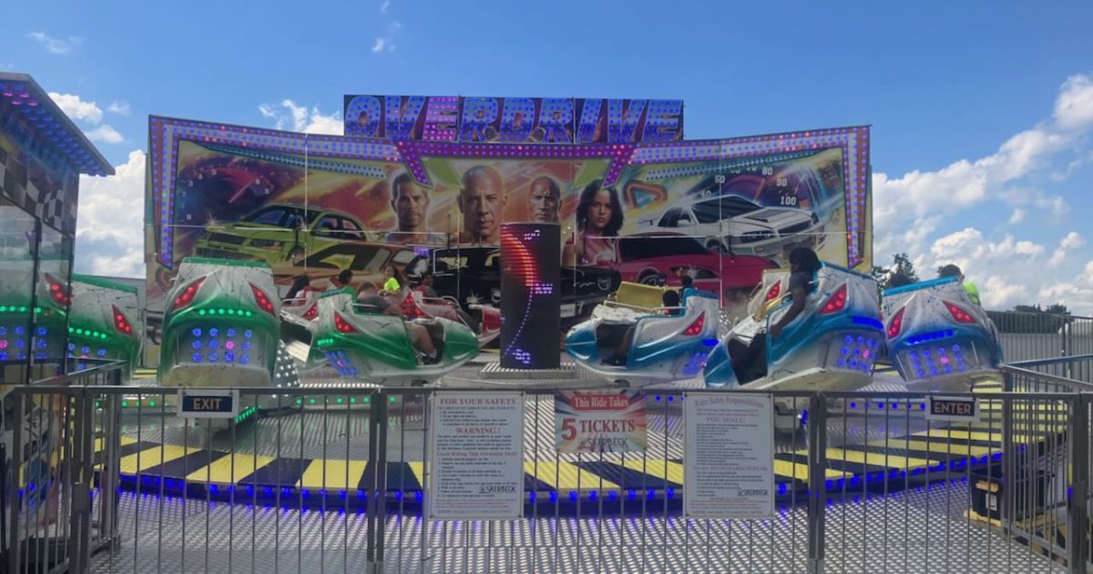 Ann Arbor Jaycees Carnival - Overdrive ride - cars that spin in small circles while rotating in a larger circle. Backdrop features cars & characters similar to Fast & Furious