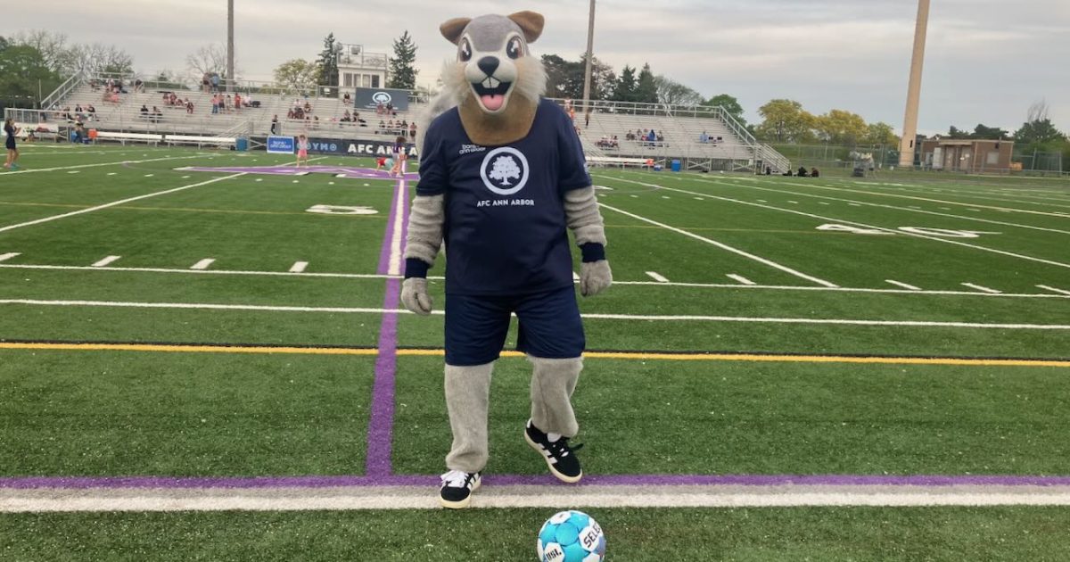 Nutmeg, the AFC Ann Arbor Mascot on the field ready to kick a ball