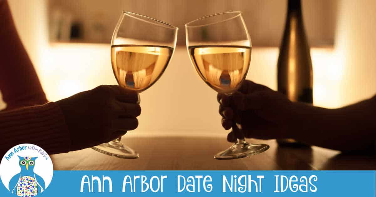 Ann Arbor Date Night Ideas - Two wine glasses clinking in a toast - suggests a couple on date night. Hands holding glasses are in silhouette.