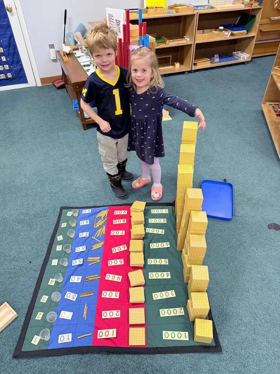 two kids stand by stacks of blocks representing different numbers