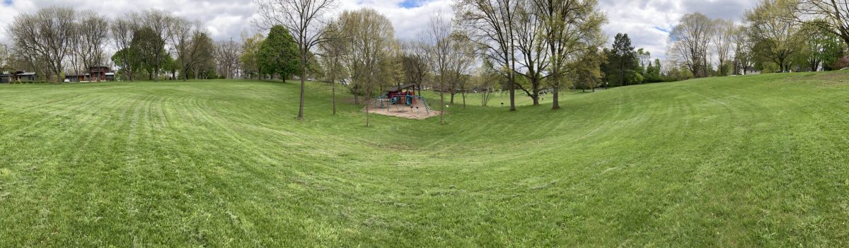 Hunt Park Panorama - playground at the center with grassy hills around t and houses in the background