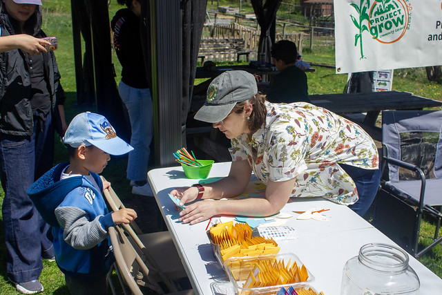 LSNC Earth Day Festival - An adult volunteer demonstrates to a child at an event table Photo provided by LSNC