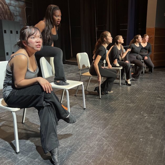 Teen actresses dressed in black sit on chairs performing "Cell Block Tango" from Pioneer Theatre Guild's production of Chicago: Teen Edition