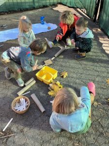 Green Apple Garden Upper School - kids sit inside a fence building.a path with paper towel tubes and popsicle sticks.
